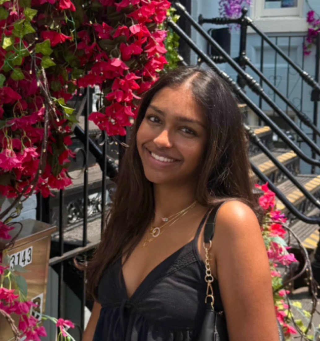Meenal smiling on a stoop with pink bougainvillea